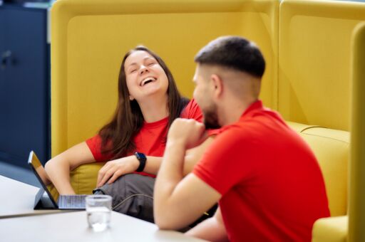 zwei Lehrlinge in einer Sitzecke lachen herzhaft