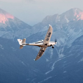 Sportflugzeug in der Luft vor einer Berglandschaft
